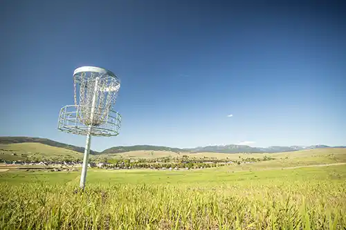 A picture of a disc golf cage set among a beautiful backdrop